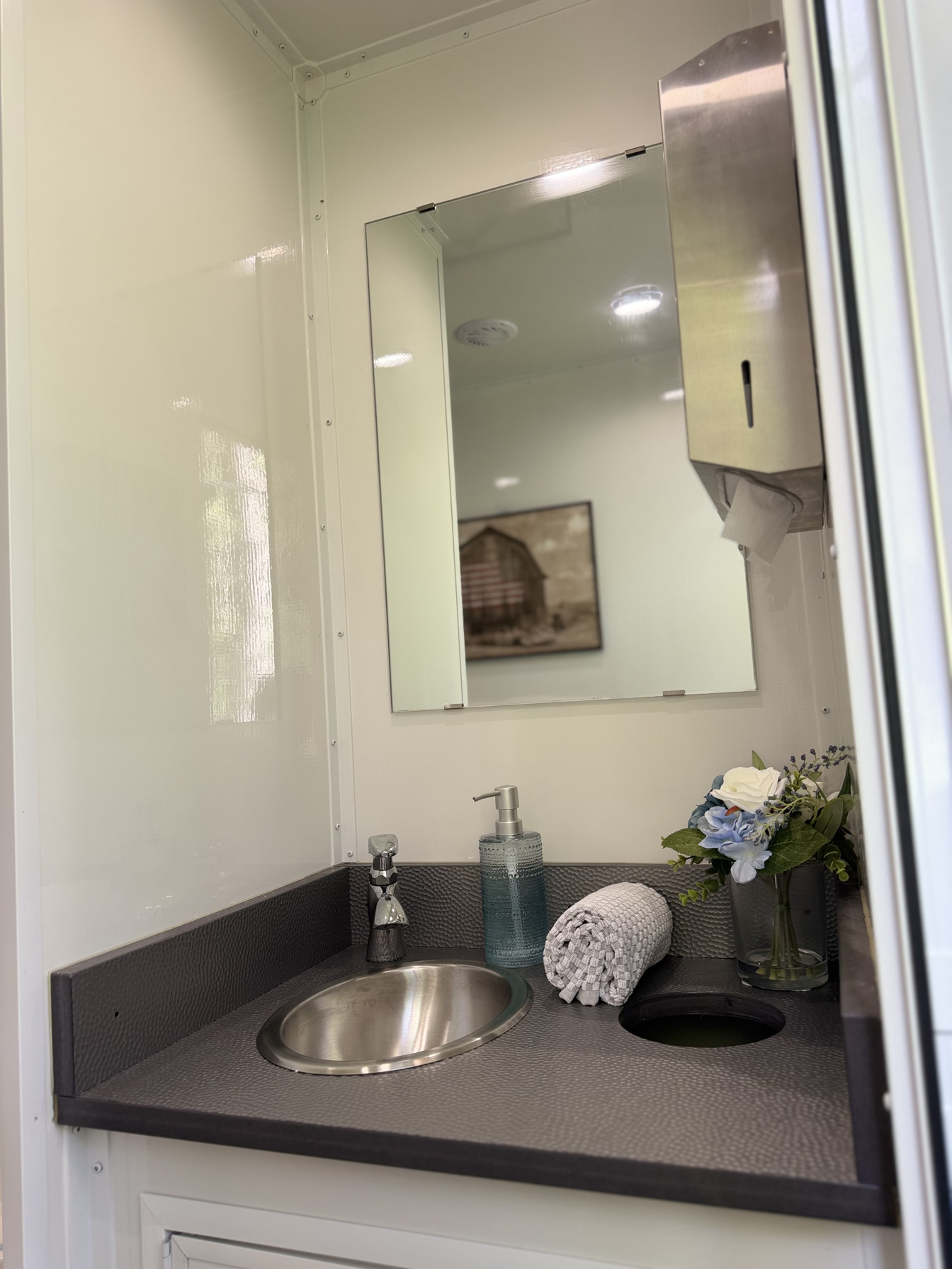 Men’s vanity sink with mirror and running water in restroom trailer